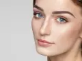 Delikatne rysy twarzy, podkreślone subtelnie zaznaczone mięśnie brody, błękitne oczy i perfekcyjny makijaż.