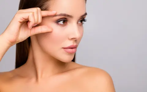 Kobieta bada swoją skórę, która po zabiegu skin booster jest nawilżona i promienna.