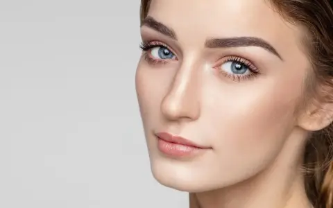 Delikatne rysy twarzy, podkreślone subtelnie zaznaczone mięśnie brody, błękitne oczy i perfekcyjny makijaż.